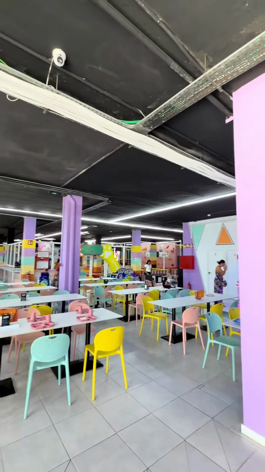 Zona de cafetería con mesas y sillas de colores