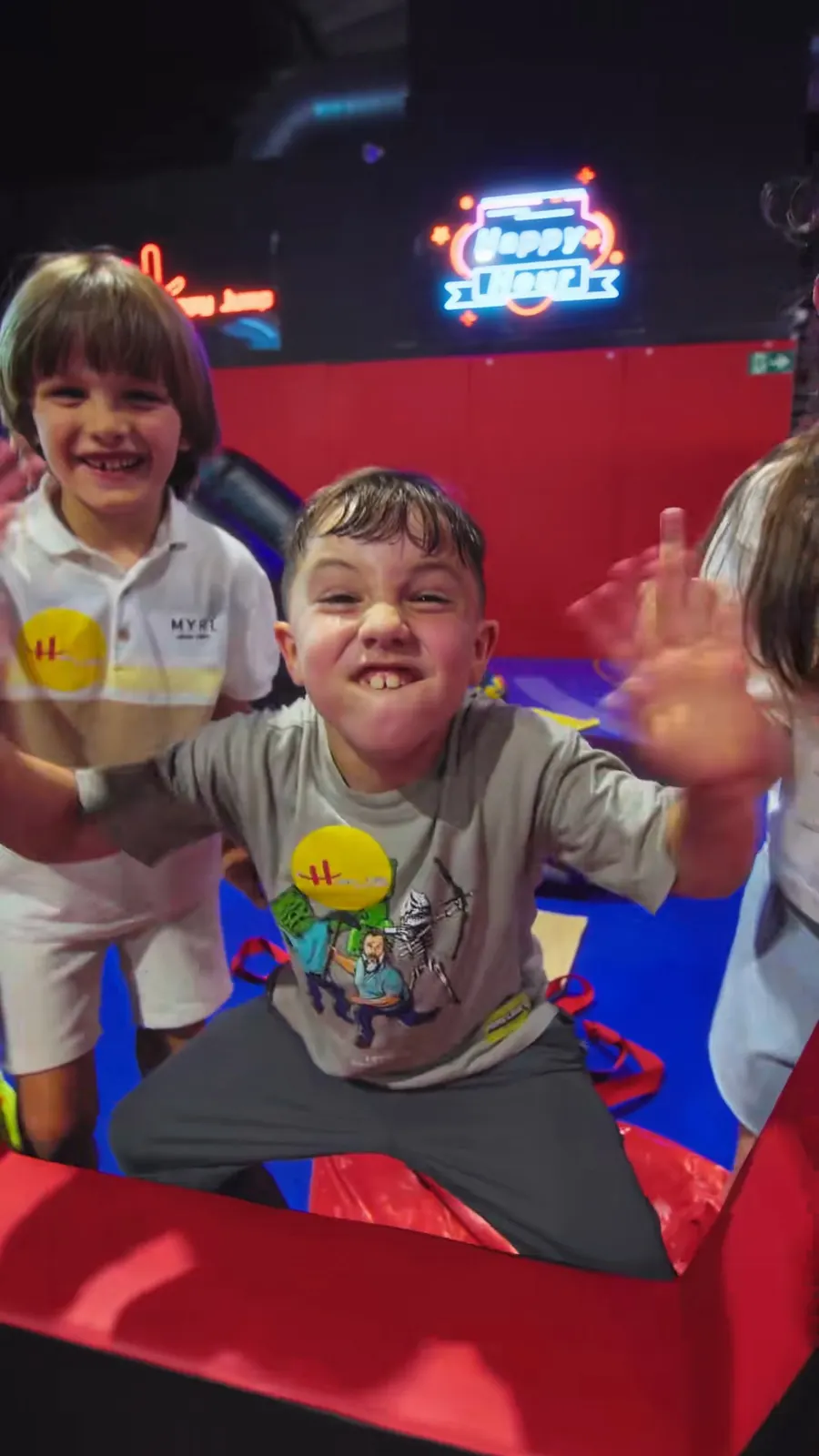 Niños saludando a la cámara desde lo alto de un tobogán